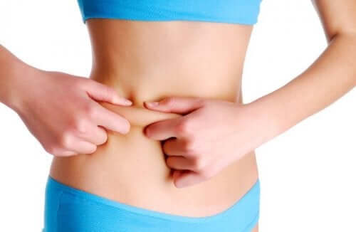 Körperfett verbrennen - Frau kneift sich in den Bauch